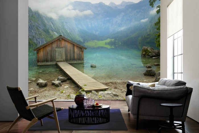 Im Wohnzimmer die Fototapete Bergsee mit Hütte, Bootshaus am Obersee auf einer großen Wand tapeziert. Die Fototapete Bergsee mit Hütte, Bootshaus am Obersee ist als Vlies-Fototapete im Wohnzimmer leicht zu tapezieren.