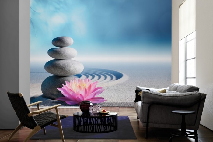 Im Wohnzimmer die Fototapete Wellness, Wellness-Steine und Seerose im Sand auf einer großen Wand tapeziert. Die Fototapete Wellness, Wellness-Steine und Seerose im Sand ist als Vlies-Fototapete im Wohnzimmer leicht zu tapezieren.