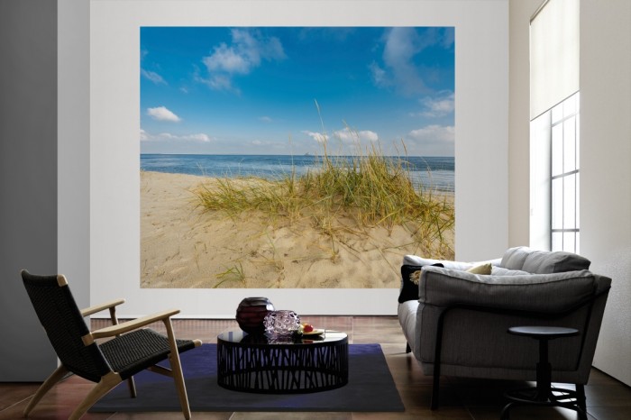 Die Fototapete Sylt, Düne am Meer bei Sonnenschein als große Bildtapete im Wohnzimmer. Als Bildtapete ist die Fototapete Sylt, Düne am Meer bei Sonnenschein ein besonderes Highlight auf Vliestapete.