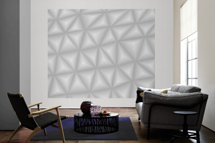 Die Design-Fototapete 3D-Geometrie graue Dreiecke als große Bildtapete im Wohnzimmer. Als Bildtapete ist die Design-Fototapete 3D-Geometrie graue Dreiecke ein besonderes Highlight auf Vliestapete.