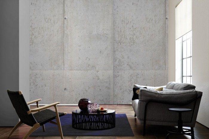 Im Wohnzimmer die Fototapete Beton Wand, Sichtbeton auf einer großen Wand tapeziert. Die Fototapete Beton Wand, Sichtbeton ist als Vlies-Fototapete im Wohnzimmer leicht zu tapezieren.