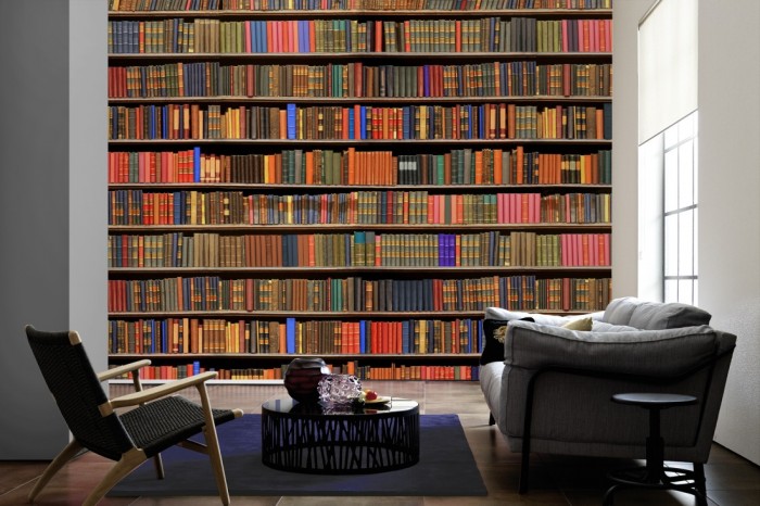 Im Wohnzimmer die Fototapete Bücherregal einer Bibliothek auf einer großen Wand tapeziert. Die Fototapete Bücherregal einer Bibliothek ist als Vlies-Fototapete im Wohnzimmer leicht zu tapezieren.