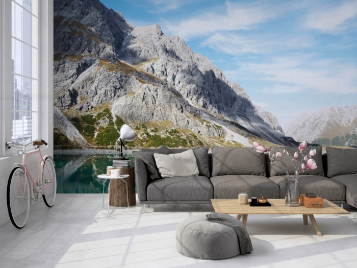 Die Fototapete Stiller Bergsee in den Alpen auf einer großen Wand im Loft tapeziert. Die Fototapete Stiller Bergsee in den Alpen wird individuell auf Deine Wand angepasst.