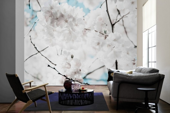 Im Wohnzimmer die Fototapete Kirschblüten in Weiß auf einer großen Wand tapeziert. Die Fototapete Kirschblüten in Weiß ist als Vlies-Fototapete im Wohnzimmer leicht zu tapezieren.