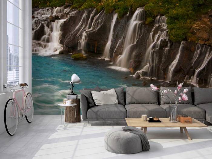 Die Fototapete Wasserfall in Island, Hraunfossar auf einer großen Wand im Loft tapeziert. Die Fototapete Wasserfall in Island, Hraunfossar wird individuell auf Deine Wand angepasst.