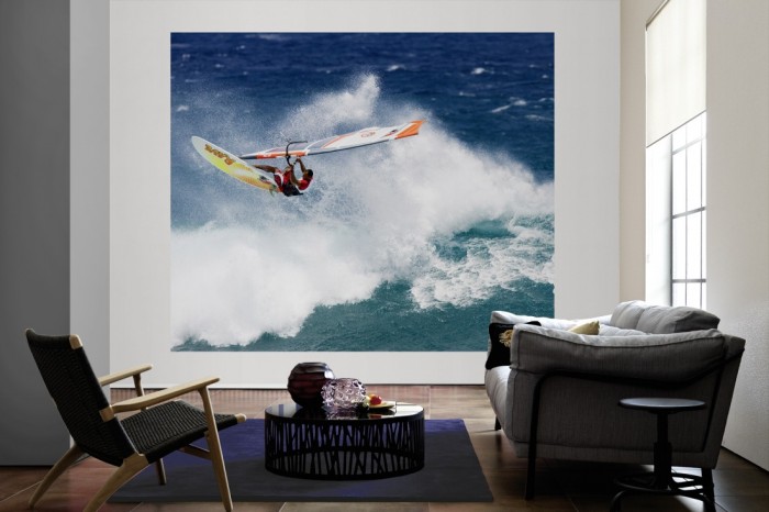 Die Fototapete Surfer auf großer Welle als große Bildtapete im Wohnzimmer. Als Bildtapete ist die Fototapete Surfer auf großer Welle ein besonderes Highlight auf Vliestapete.