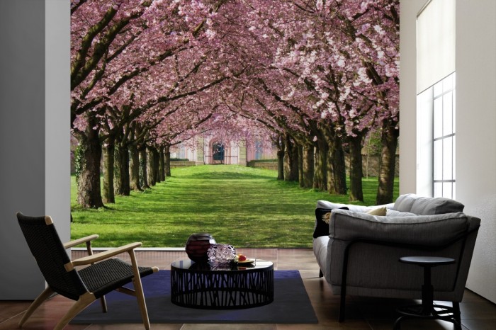 Im Wohnzimmer die Fototapete Kischblüten Baum-Allee auf einer großen Wand tapeziert. Die Fototapete Kischblüten Baum-Allee ist als Vlies-Fototapete im Wohnzimmer leicht zu tapezieren.