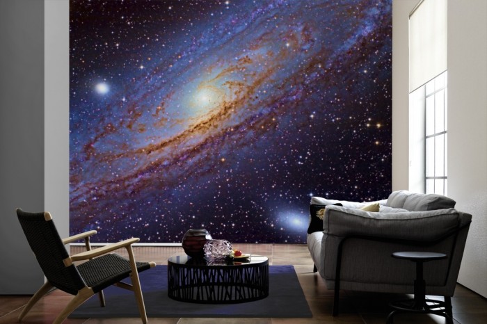 Im Wohnzimmer die Fototapete Weltraum Galaxie auf einer großen Wand tapeziert. Die Fototapete Weltraum Galaxie ist als Vlies-Fototapete im Wohnzimmer leicht zu tapezieren.