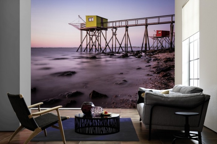 Im Wohnzimmer die Fototapete Hütten der Fischerei am Meer auf einer großen Wand tapeziert. Die Fototapete Hütten der Fischerei am Meer ist als Vlies-Fototapete im Wohnzimmer leicht zu tapezieren.