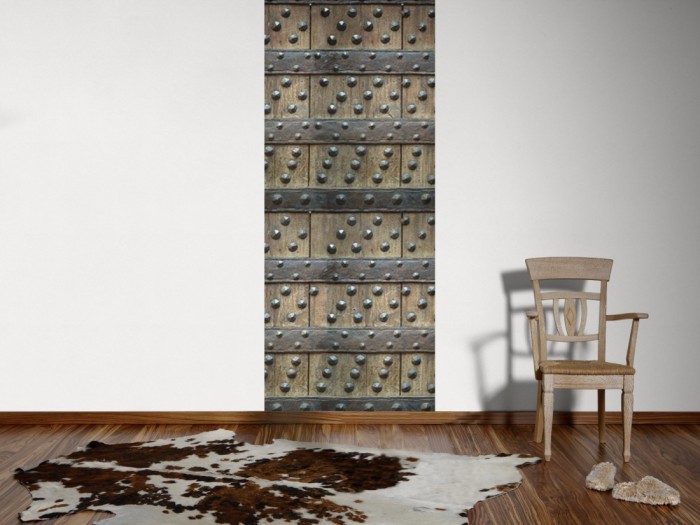 Ein Foto von dem 3D Fotopanel Alte Holztür mit Eisennieten tapeziert an der Wand. Bestelle Deine Bildtapete online.
