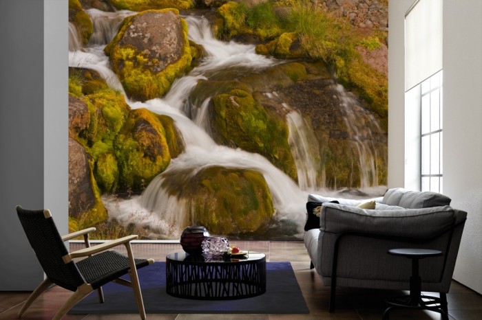 Im Wohnzimmer die Fototapete Wasserfall im Gebirge auf einer großen Wand tapeziert. Die Fototapete Wasserfall im Gebirge ist als Vlies-Fototapete im Wohnzimmer leicht zu tapezieren.