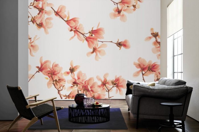 Im Wohnzimmer die Fototapete Magnolie Äste in Rosa auf einer großen Wand tapeziert. Die Fototapete Magnolie Äste in Rosa ist als Vlies-Fototapete im Wohnzimmer leicht zu tapezieren.