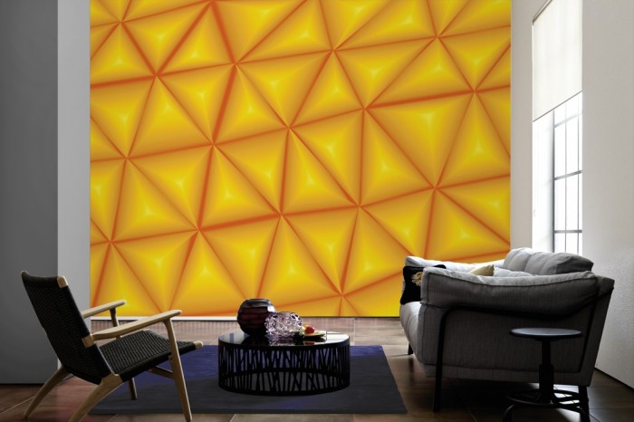 Im Wohnzimmer die Design-Fototapete 3D-Geometrie orangene Dreiecke auf einer großen Wand tapeziert. Die Design-Fototapete 3D-Geometrie orangene Dreiecke ist als Vlies-Fototapete im Wohnzimmer leicht zu tapezieren.