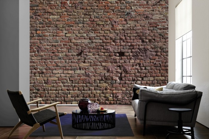 Im Wohnzimmer die Fototapete Ziegel Wand, Steine im Sonnenschein auf einer großen Wand tapeziert. Die Fototapete Ziegel Wand, Steine im Sonnenschein ist als Vlies-Fototapete im Wohnzimmer leicht zu tapezieren.