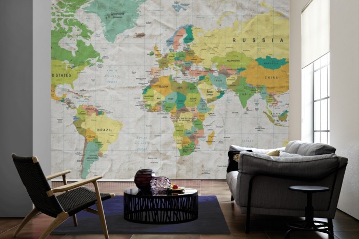 Im Wohnzimmer die Fototapete Weltkarte, farbig im Vintage-Look auf einer großen Wand tapeziert. Die Fototapete Weltkarte, farbig im Vintage-Look ist als Vlies-Fototapete im Wohnzimmer leicht zu tapezieren.