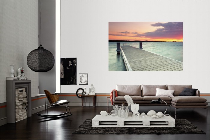 Die Fototapete Steg im See bei Sonnenaufgang als Wandbild im Wohnzimmer. Die Vlies-Fototapete Steg im See bei Sonnenaufgang verschönert als Wandbild Deine Wand.