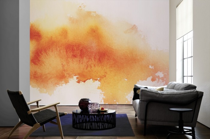 Im Wohnzimmer die Design-Fototapete Verlauf der Wasserfarbe in Orange auf einer großen Wand tapeziert. Die Design-Fototapete Verlauf der Wasserfarbe in Orange ist als Vlies-Fototapete im Wohnzimmer leicht zu tapezieren.