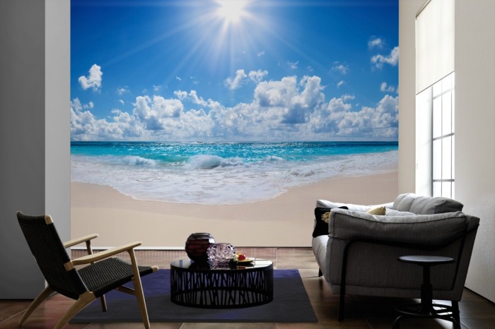 Im Wohnzimmer die Fototapete Sandstrand im Sonnenschein auf einer großen Wand tapeziert. Die Fototapete Sandstrand im Sonnenschein ist als Vlies-Fototapete im Wohnzimmer leicht zu tapezieren.