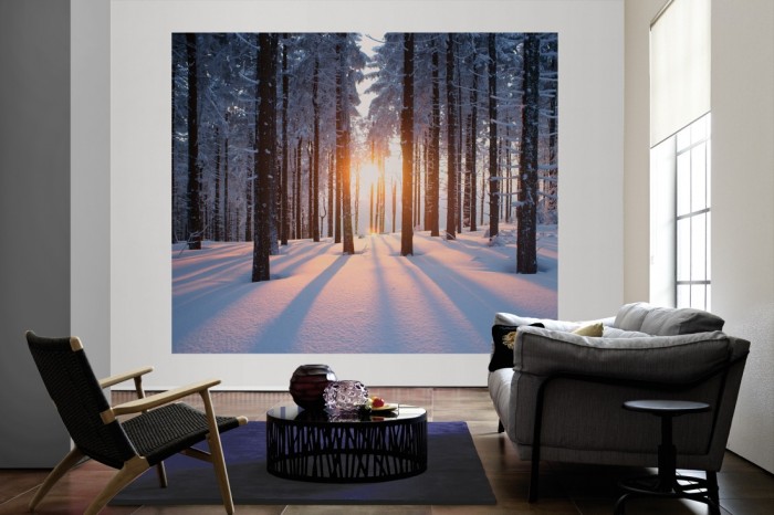 Die Fototapete Wald im Schnee bei Sonnenaufgang als große Bildtapete im Wohnzimmer. Als Bildtapete ist die Fototapete Wald im Schnee bei Sonnenaufgang ein besonderes Highlight auf Vliestapete.