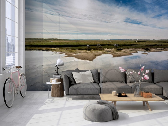 Die Fototapete Landschaft mit Schafen im Sonnenschein auf einer großen Wand im Loft tapeziert. Die Fototapete Landschaft mit Schafen im Sonnenschein wird individuell auf Deine Wand angepasst.