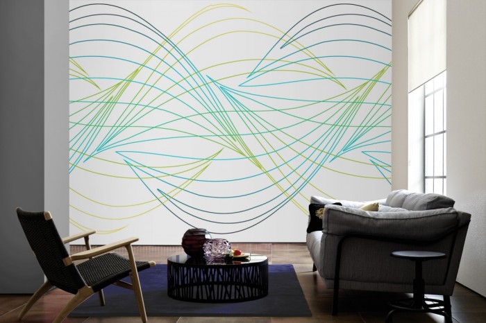 Im Wohnzimmer die Design-Fototapete Geometrie Wellen in Grün auf einer großen Wand tapeziert. Die Design-Fototapete Geometrie Wellen in Grün ist als Vlies-Fototapete im Wohnzimmer leicht zu tapezieren.