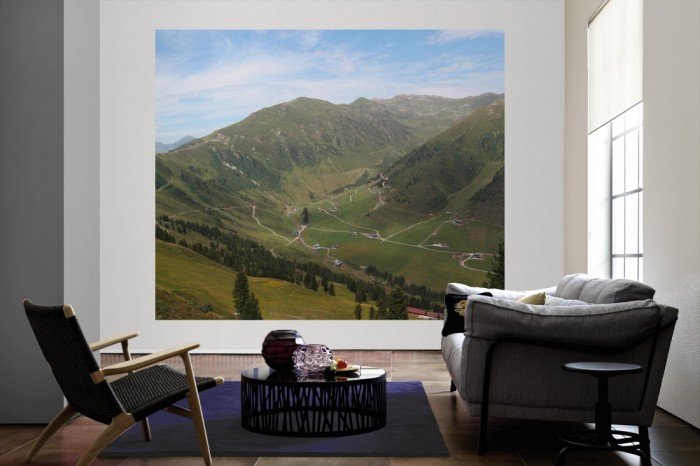 Die Fototapete Alpen Österreich, Grünes Tal als große Bildtapete im Wohnzimmer. Als Bildtapete ist die Fototapete Alpen Österreich, Grünes Tal ein besonderes Highlight auf Vliestapete.