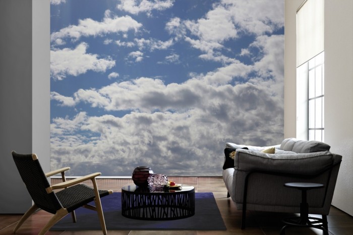 Im Wohnzimmer die Fototapete Wolkenhimmel bei Sonnenschein auf einer großen Wand tapeziert. Die Fototapete Wolkenhimmel bei Sonnenschein ist als Vlies-Fototapete im Wohnzimmer leicht zu tapezieren.