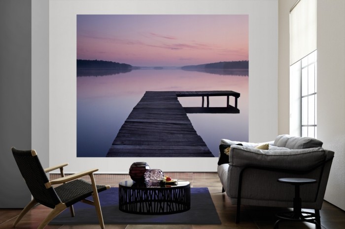 Die Fototapete See mit Steg im Morgengrauen als große Bildtapete im Wohnzimmer. Als Bildtapete ist die Fototapete See mit Steg im Morgengrauen ein besonderes Highlight auf Vliestapete.