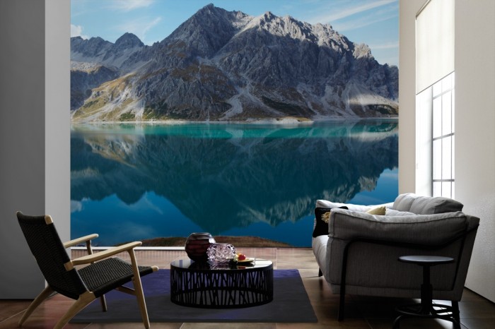 Im Wohnzimmer die Fototapete Einsamer Bergsee in den Alpen auf einer großen Wand tapeziert. Die Fototapete Einsamer Bergsee in den Alpen ist als Vlies-Fototapete im Wohnzimmer leicht zu tapezieren.