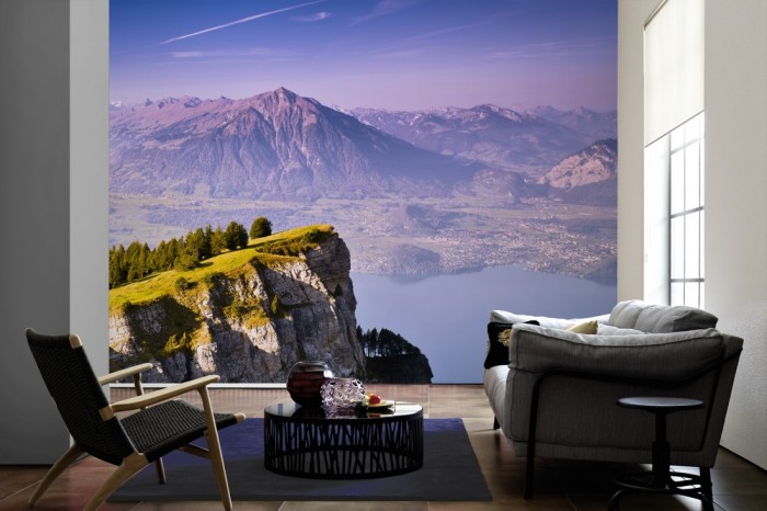 Im Wohnzimmer die Fototapete Gebirge am See in der Schweiz auf einer großen Wand tapeziert. Die Fototapete Gebirge am See in der Schweiz ist als Vlies-Fototapete im Wohnzimmer leicht zu tapezieren.