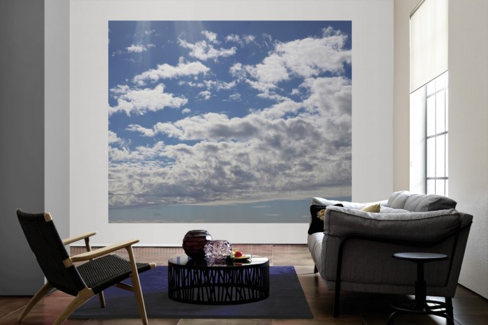 Die Fototapete Wolkenhimmel bei Sonnenschein als große Bildtapete im Wohnzimmer. Als Bildtapete ist die Fototapete Wolkenhimmel bei Sonnenschein ein besonderes Highlight auf Vliestapete.
