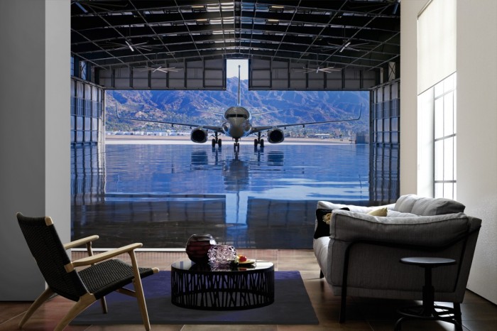 Im Wohnzimmer die Fototapete Flugzeug im Hangar auf einer großen Wand tapeziert. Die Fototapete Flugzeug im Hangar ist als Vlies-Fototapete im Wohnzimmer leicht zu tapezieren.