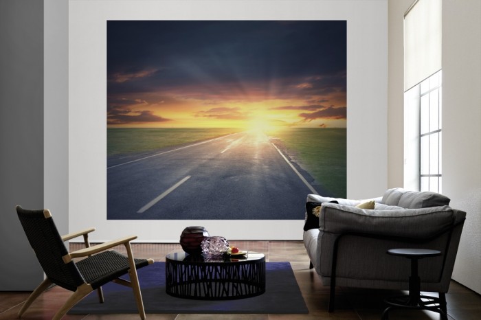 Die Fototapete Straße bei Sonnenaufgang als große Bildtapete im Wohnzimmer. Als Bildtapete ist die Fototapete Straße bei Sonnenaufgang ein besonderes Highlight auf Vliestapete.