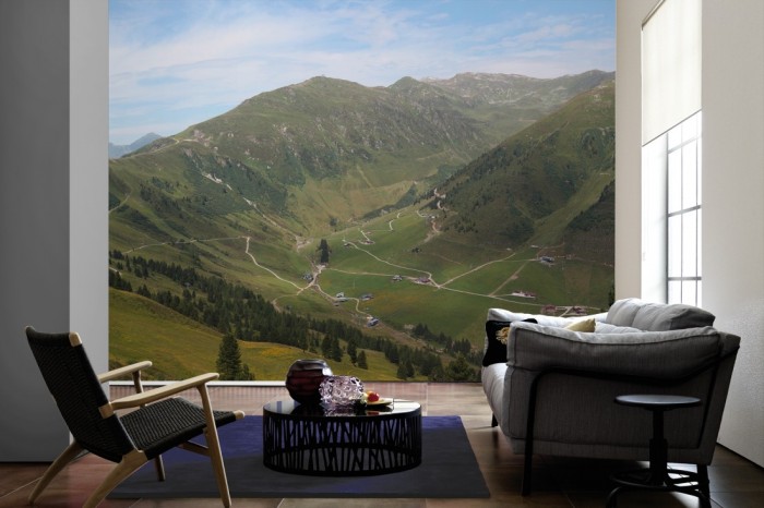 Im Wohnzimmer die Fototapete Alpen Österreich, Grünes Tal auf einer großen Wand tapeziert. Die Fototapete Alpen Österreich, Grünes Tal ist als Vlies-Fototapete im Wohnzimmer leicht zu tapezieren.