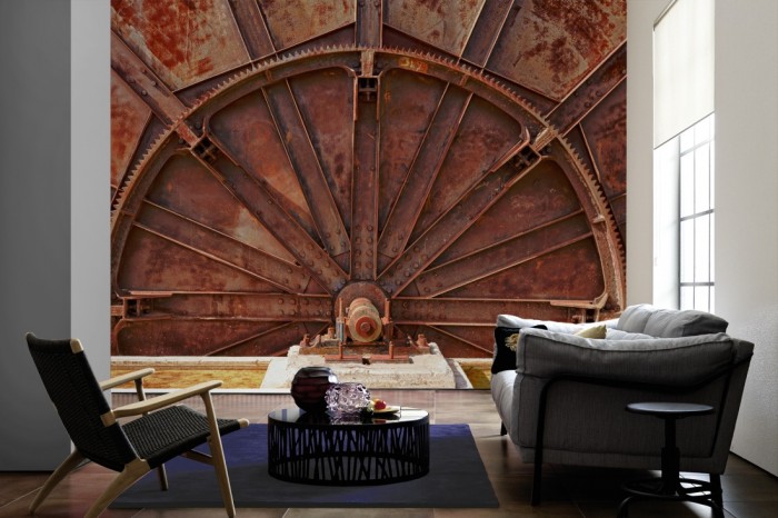 Im Wohnzimmer die Fototapete Altes Maschinenrad, Industrie auf einer großen Wand tapeziert. Die Fototapete Altes Maschinenrad, Industrie ist als Vlies-Fototapete im Wohnzimmer leicht zu tapezieren.