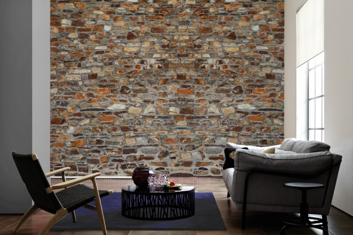 Im Wohnzimmer die Fototapete Stein Wand, Naturstein rot-braun auf einer großen Wand tapeziert. Die Fototapete Stein Wand, Naturstein rot-braun ist als Vlies-Fototapete im Wohnzimmer leicht zu tapezieren.