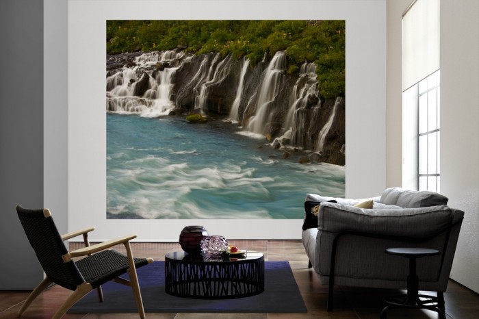 Die Fototapete Wasserfall in Island, Hraunfossar als große Bildtapete im Wohnzimmer. Als Bildtapete ist die Fototapete Wasserfall in Island, Hraunfossar ein besonderes Highlight auf Vliestapete.