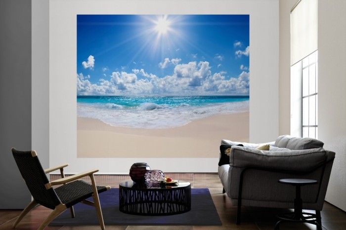Die Fototapete Sandstrand im Sonnenschein als große Bildtapete im Wohnzimmer. Als Bildtapete ist die Fototapete Sandstrand im Sonnenschein ein besonderes Highlight auf Vliestapete.