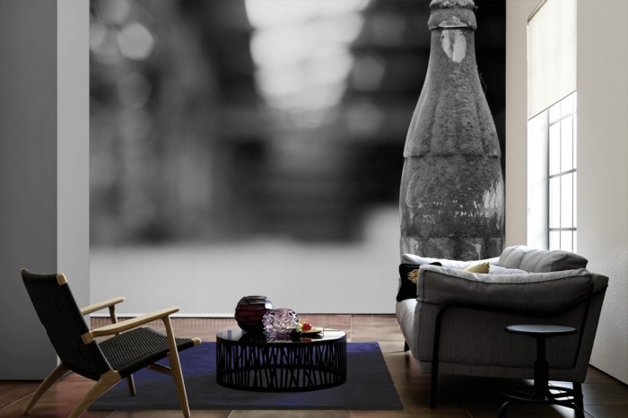 Im Wohnzimmer die Fototapete Coke Flasche, schwarz-weiß auf einer großen Wand tapeziert. Die Fototapete Coke Flasche, schwarz-weiß ist als Vlies-Fototapete im Wohnzimmer leicht zu tapezieren.