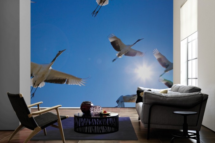 Im Wohnzimmer die Fototapete Vögel im Himmel, Kraniche auf einer großen Wand tapeziert. Die Fototapete Vögel im Himmel, Kraniche ist als Vlies-Fototapete im Wohnzimmer leicht zu tapezieren.