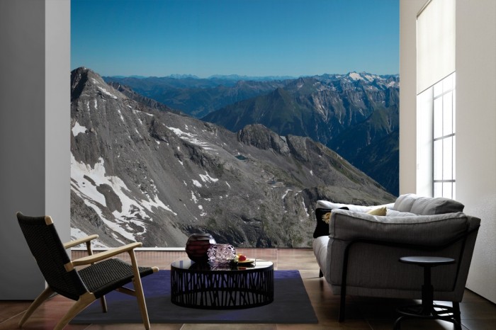 Im Wohnzimmer die Fototapete Alpen Österreich, Panorama der Berge auf einer großen Wand tapeziert. Die Fototapete Alpen Österreich, Panorama der Berge ist als Vlies-Fototapete im Wohnzimmer leicht zu tapezieren.