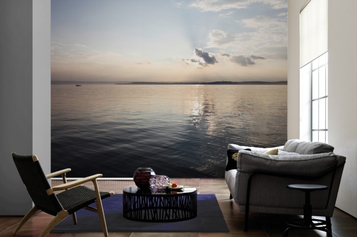 Im Wohnzimmer die Fototapete Stiller See in der Morgensonne auf einer großen Wand tapeziert. Die Fototapete Stiller See in der Morgensonne ist als Vlies-Fototapete im Wohnzimmer leicht zu tapezieren.
