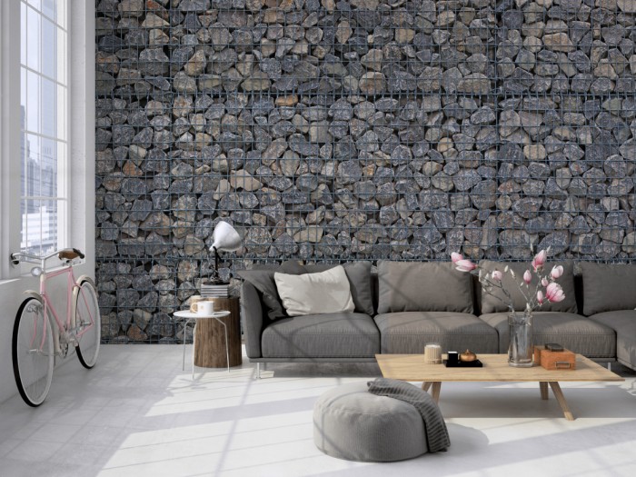 Die Fototapete Stein Wand, Steine in Gabionen auf einer großen Wand im Loft tapeziert. Die Fototapete Stein Wand, Steine in Gabionen wird individuell auf Deine Wand angepasst.