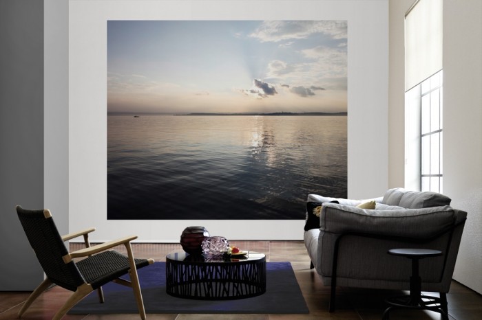 Die Fototapete Stiller See in der Morgensonne als große Bildtapete im Wohnzimmer. Als Bildtapete ist die Fototapete Stiller See in der Morgensonne ein besonderes Highlight auf Vliestapete.