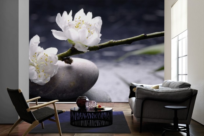 Im Wohnzimmer die Fototapete Wellness, Wellness-Steine mit Kirschblüte auf einer großen Wand tapeziert. Die Fototapete Wellness, Wellness-Steine mit Kirschblüte ist als Vlies-Fototapete im Wohnzimmer leicht zu tapezieren.