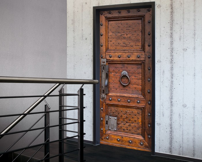 Ein Foto von der selbstklebenden Türtapete Alte Holztür aus Eiche mit Nieten tapeziert auf einer Tür. Bestelle Deine Türtapete online.