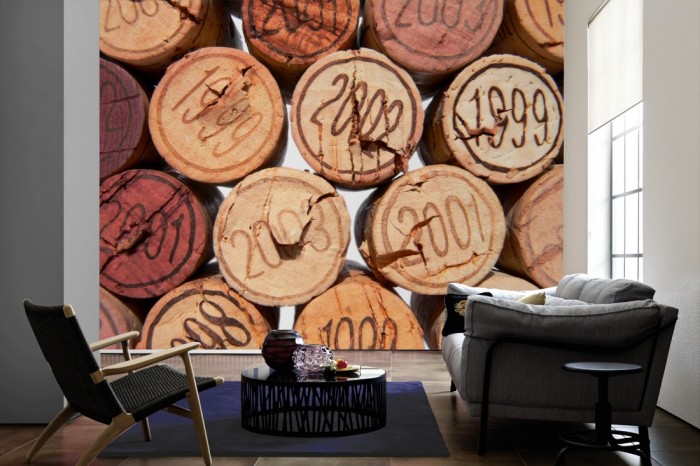 Im Wohnzimmer die Fototapete Wein, Korken mit Jahrgängen auf einer großen Wand tapeziert. Die Fototapete Wein, Korken mit Jahrgängen ist als Vlies-Fototapete im Wohnzimmer leicht zu tapezieren.