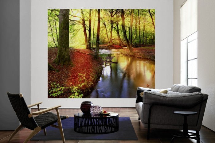 Die Fototapete Waldbach im Sonnenlicht als große Bildtapete im Wohnzimmer. Als Bildtapete ist die Fototapete Waldbach im Sonnenlicht ein besonderes Highlight auf Vliestapete.