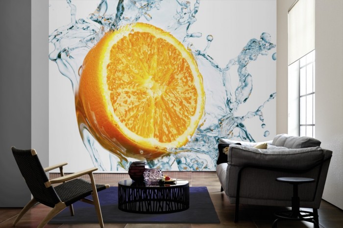 Im Wohnzimmer die Fototapete Orange mit Wasserspritzer auf einer großen Wand tapeziert. Die Fototapete Orange mit Wasserspritzer ist als Vlies-Fototapete im Wohnzimmer leicht zu tapezieren.