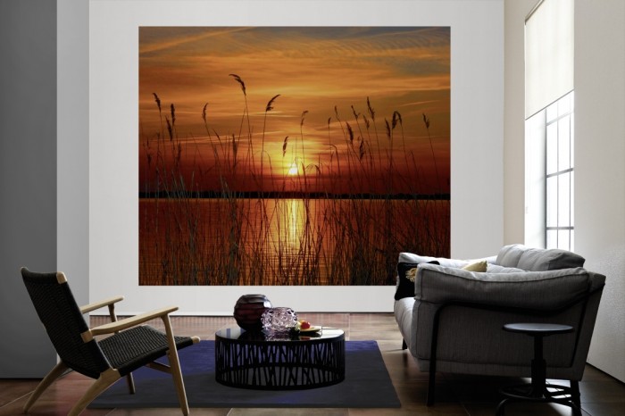 Die Fototapete Seeufer im Sonnenuntergang als große Bildtapete im Wohnzimmer. Als Bildtapete ist die Fototapete Seeufer im Sonnenuntergang ein besonderes Highlight auf Vliestapete.